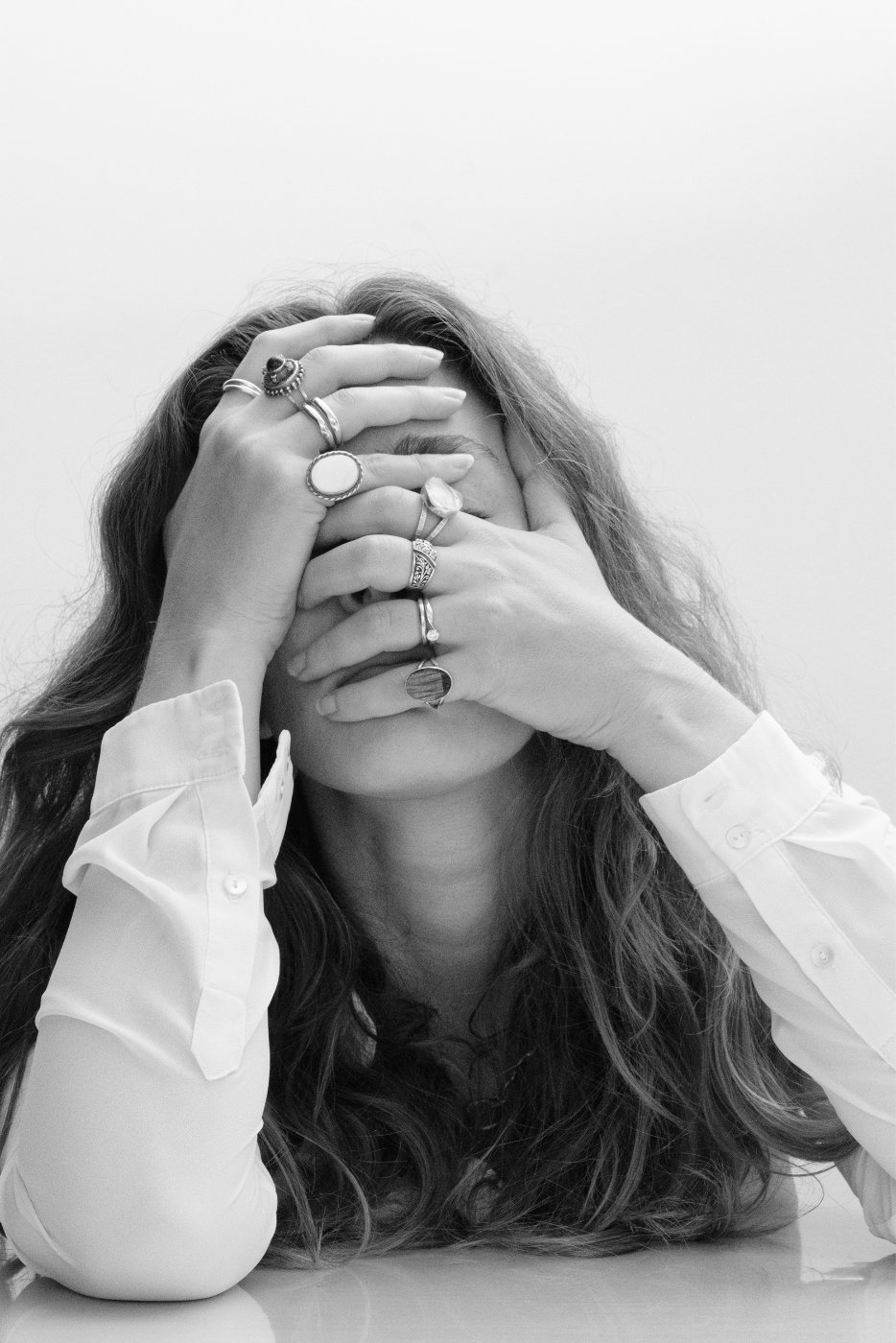 Woman with ringed hands over face