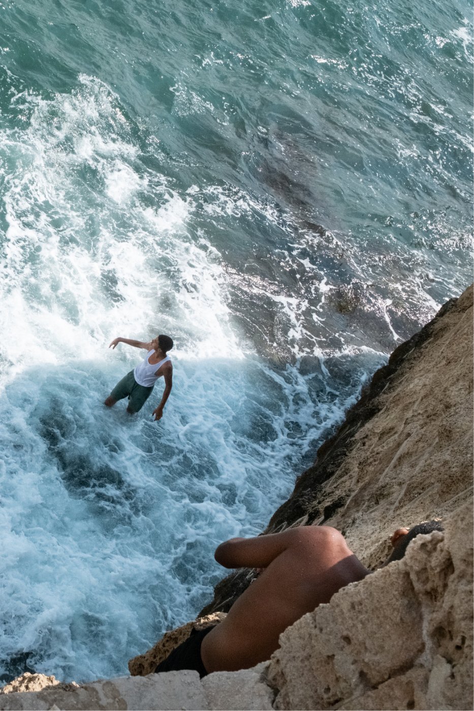 Swimmer in the waves below a cliff